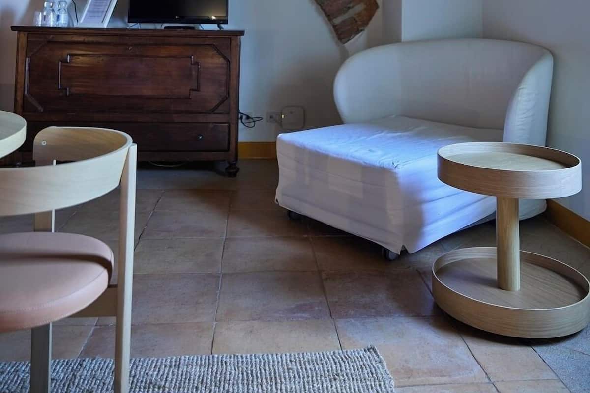 Ein Zimmer mit einem weißen Sofa, einem Holzschrank mit Fernseher, einem kleinen Tisch und einer Katzenkralle.
