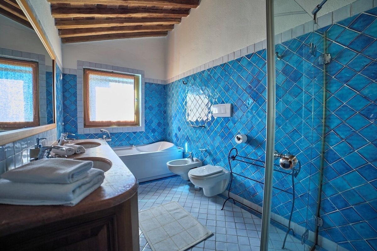Ein Badezimmer mit einer Badewanne, zwei Toiletten, einer Dusche und einem großen Fenster.
