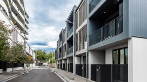 En modern stadsgata med flerfamiljshus, klar himmel och en gångbana för fotgängare.