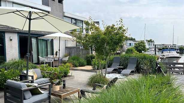 Eine moderne Außenpatio mit einer Couch, Stühlen und einem Tisch unter einem großen Sonnenschirm.