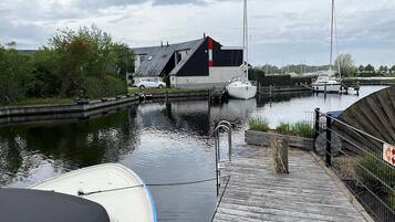 Een jachthaven met aangemeerde boten, een houten steiger en een gebouw met schuin dak.