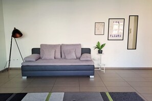 A modern living room with a sofa, a floor lamp, a small plant, and framed artwork on the wall. - Close to the Heart of Lugano (Mola Glicine) (Lugano)