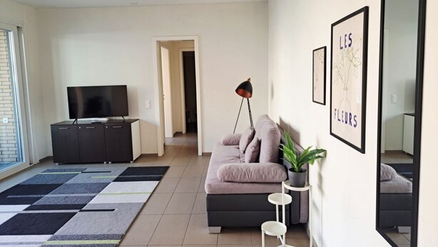 Un salon moderne avec un canapé, un téléviseur et des œuvres d’art accrochées au mur.