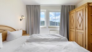 Makuuhuoneessa on sänky, yöpöytä, puinen vaatekaappi ja ikkuna, jossa on verhot.