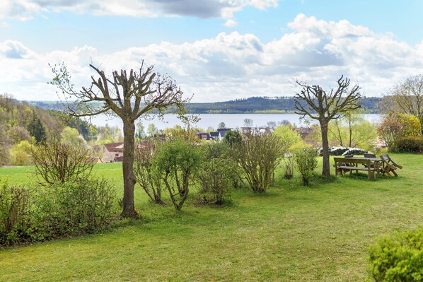 Eine grüne Wiese mit Bäumen und einem See im Hintergrund.