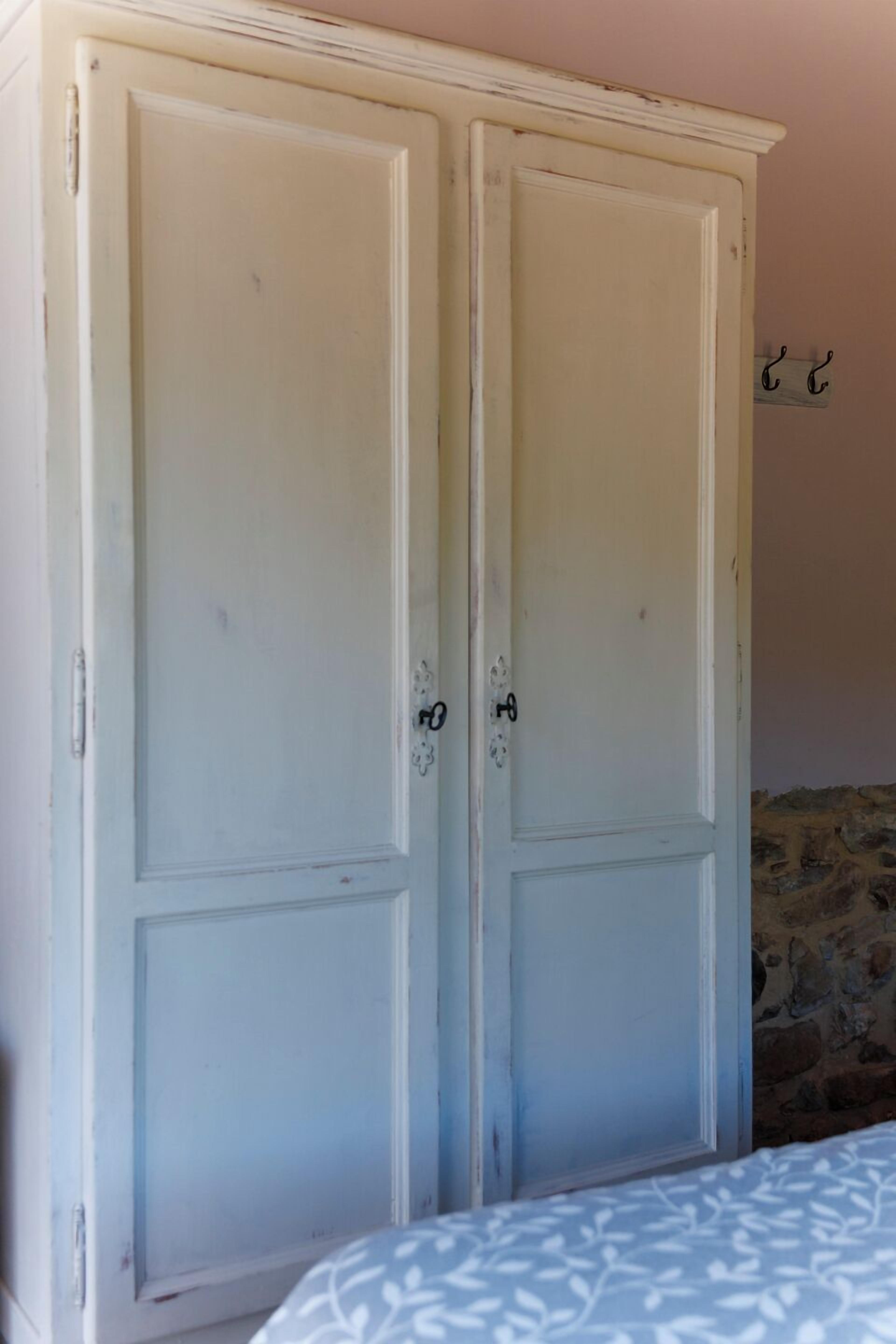 Ein Zimmer mit einer Doppeltür, einem Bett mit gemustertem Überwurf und einer Steinwand.