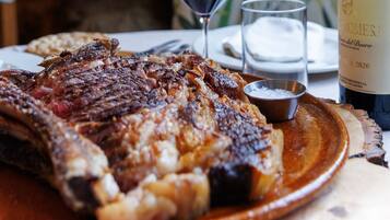 Een bord gegrild steak met brood, een glas rode wijn en een fles wijn.