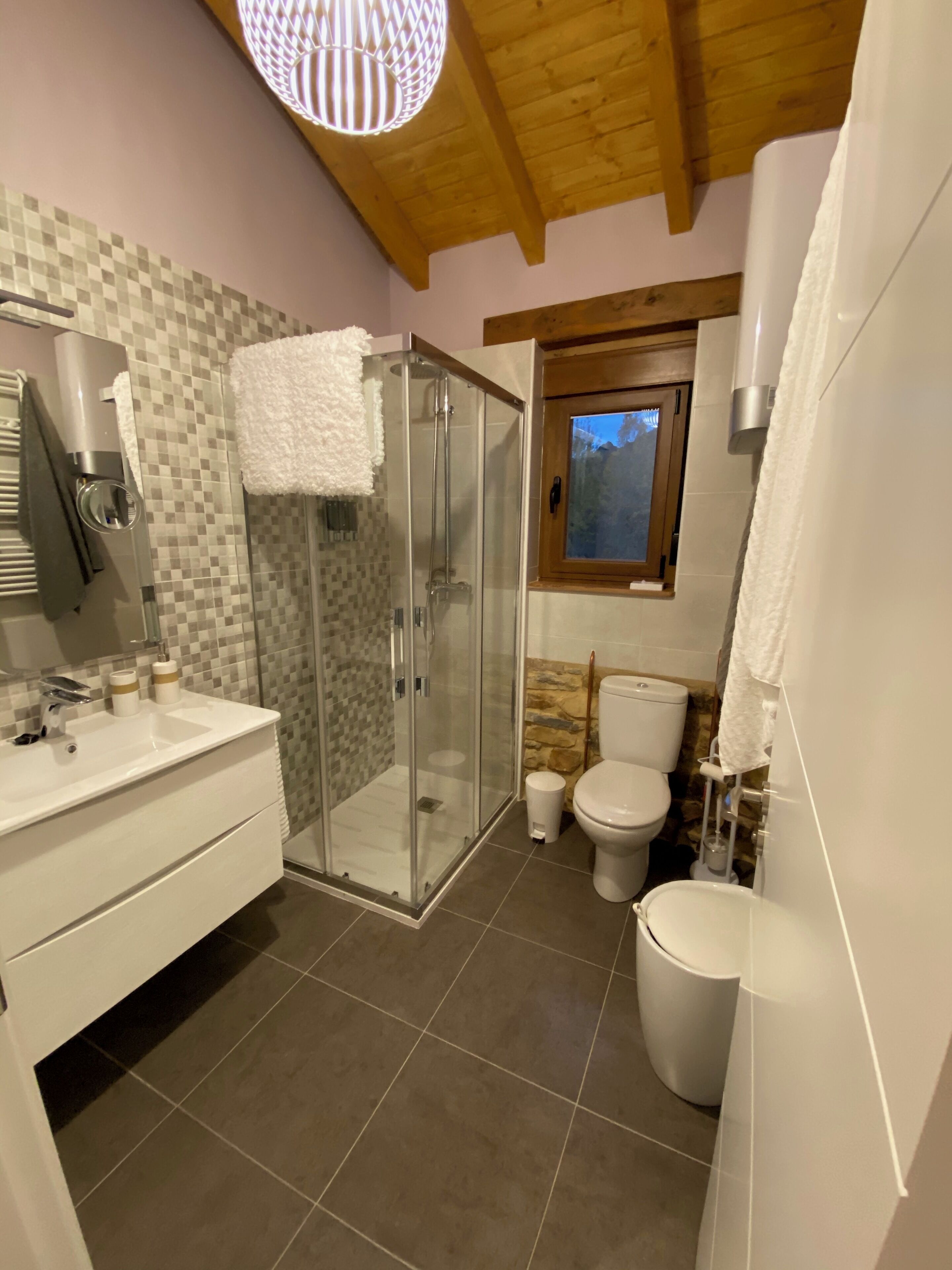 A modern bathroom with a glass-enclosed shower, a white sink, and a toilet.