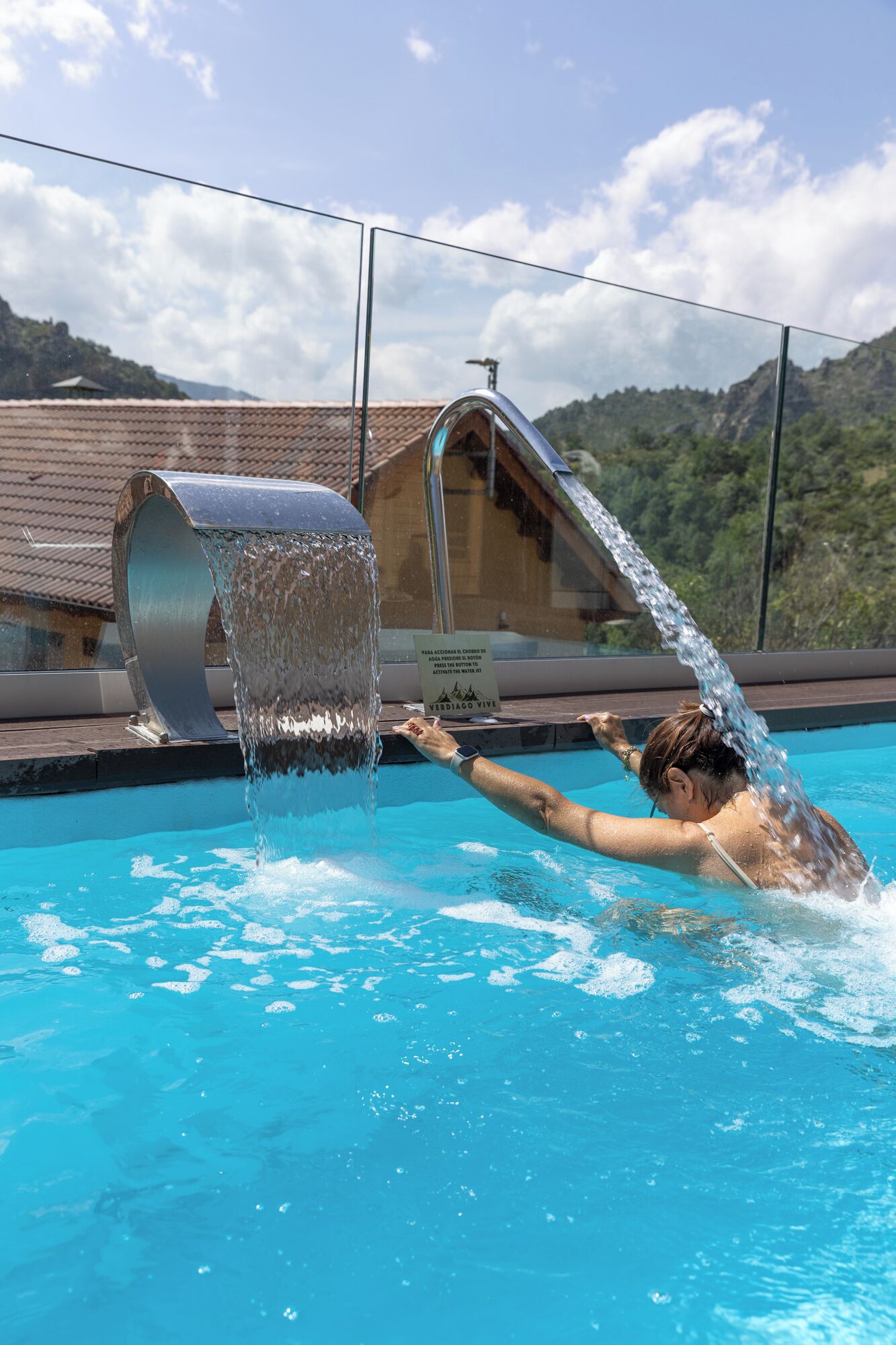 A person swimming in a pool with a water feature.