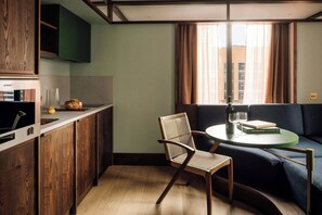 A compact kitchen with wooden cabinets, a dining area with a round table, and a sofa. - Locke London Canary Wharf (London)