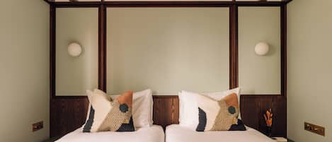 A double bed with a geometric-patterned bedspread, two pillows with a dog design, and a wooden headboard.