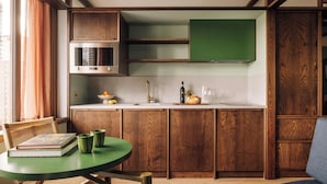 A kitchen with wooden cabinets, a green table, and a window with curtains.