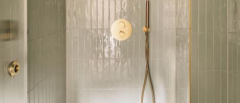 A shower area with a gold showerhead and a control panel.