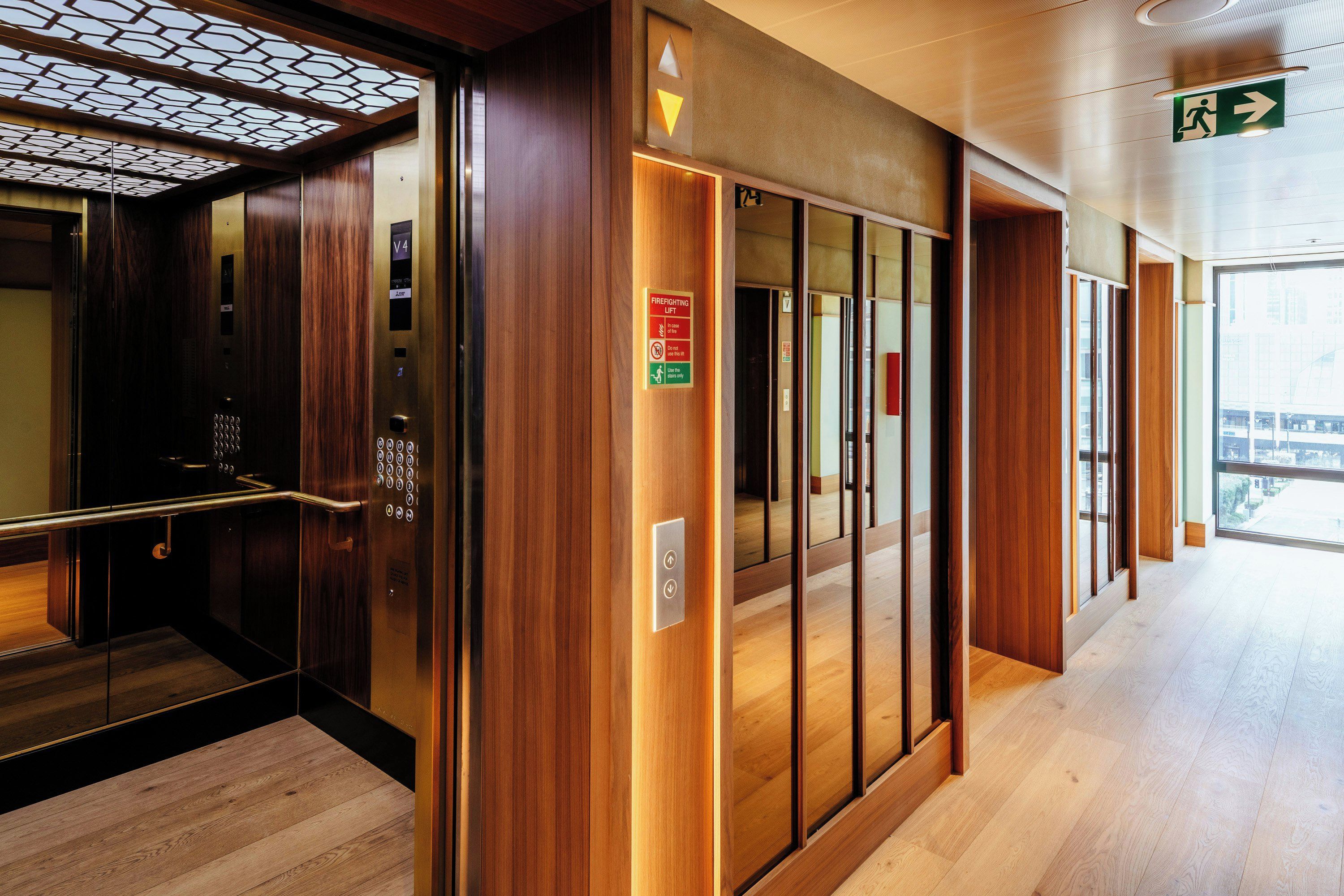 A modern elevator interior with wooden paneling and a glass door.