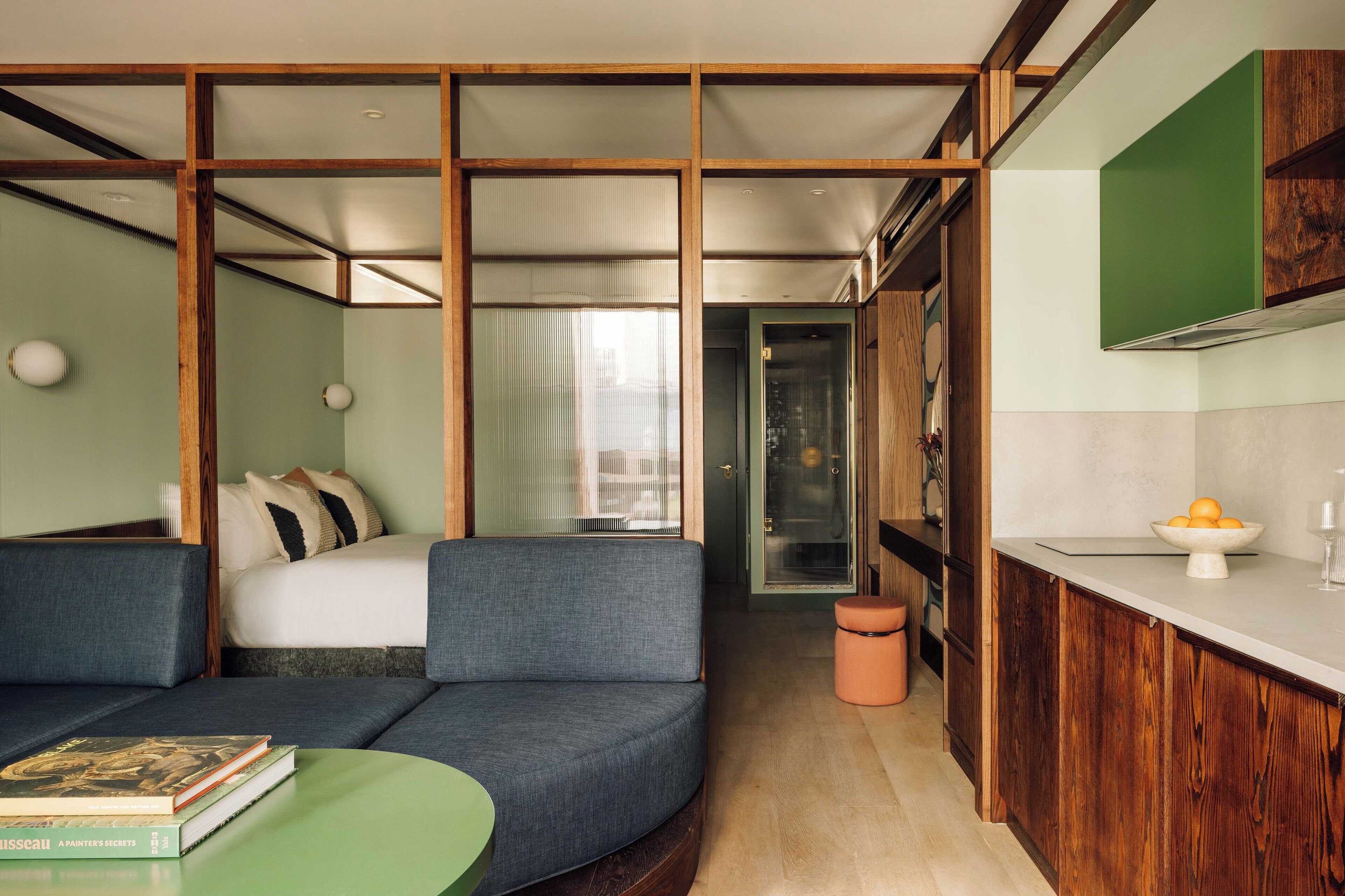 Une chambre d’hôtel moderne équipée d’un canapé, d’une petite table, d’un lit avec vue, d’un coin cuisine et d’une salle de bain.