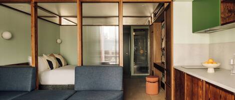 Une chambre d’hôtel moderne équipée d’un canapé, d’une petite table, d’un lit avec vue, d’un coin cuisine et d’une salle de bain.
