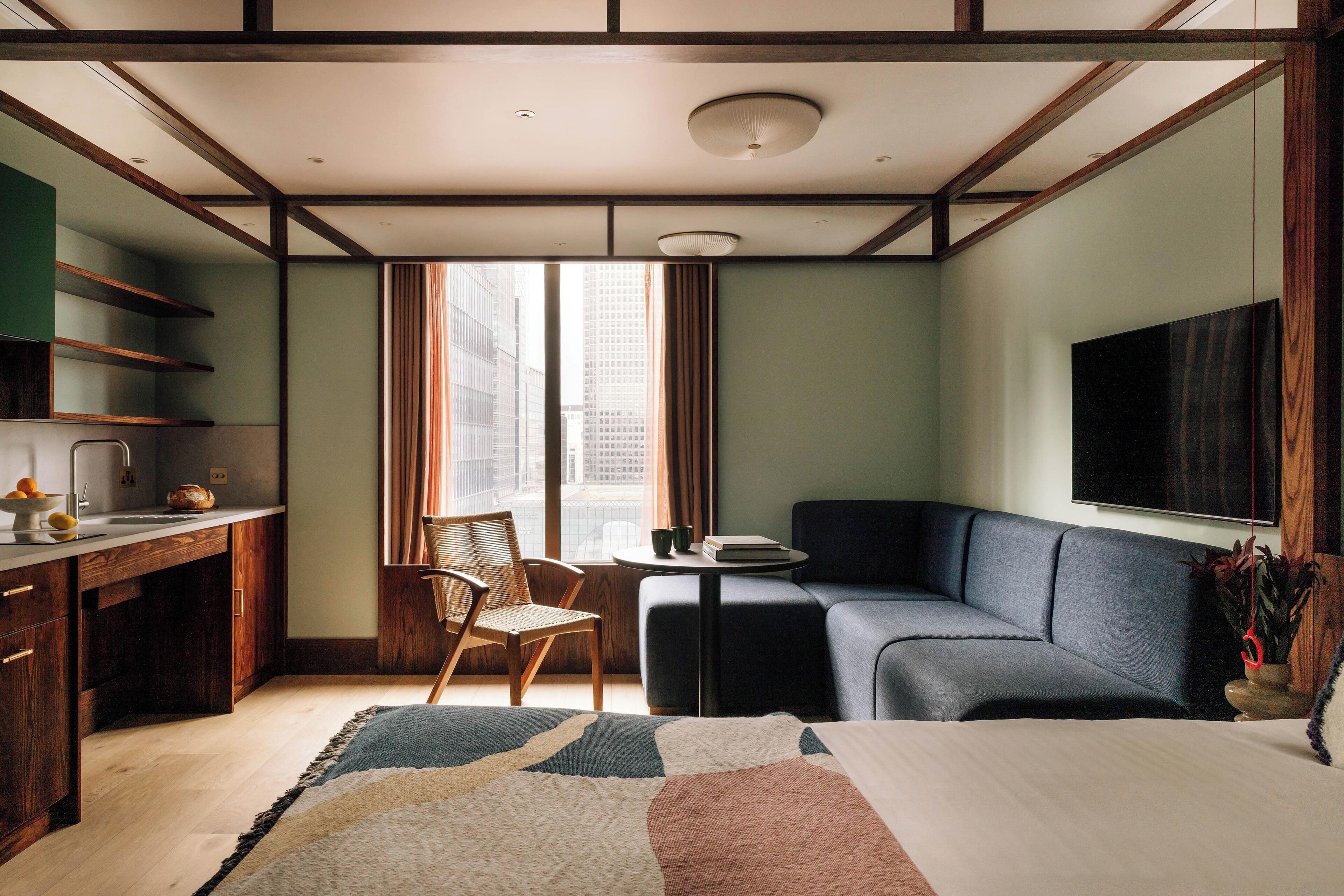 Een moderne hotelkamer met een bureau, een bank en een groot raam met uitzicht op de stad.