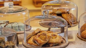 A bakery display with various pastries under glass domes, including a sign for 'Apple Danish.'
