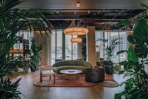 Un interior moderno con un sofá verde, una mesa redonda de madera y varias plantas.