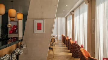 Un moderno vestíbulo de hotel con piso de madera, una mesa de recepción y un área de descanso con sillones acolchados.