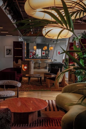 A modern interior with a bar area, seating, and plants. - Locke London Canary Wharf (London)