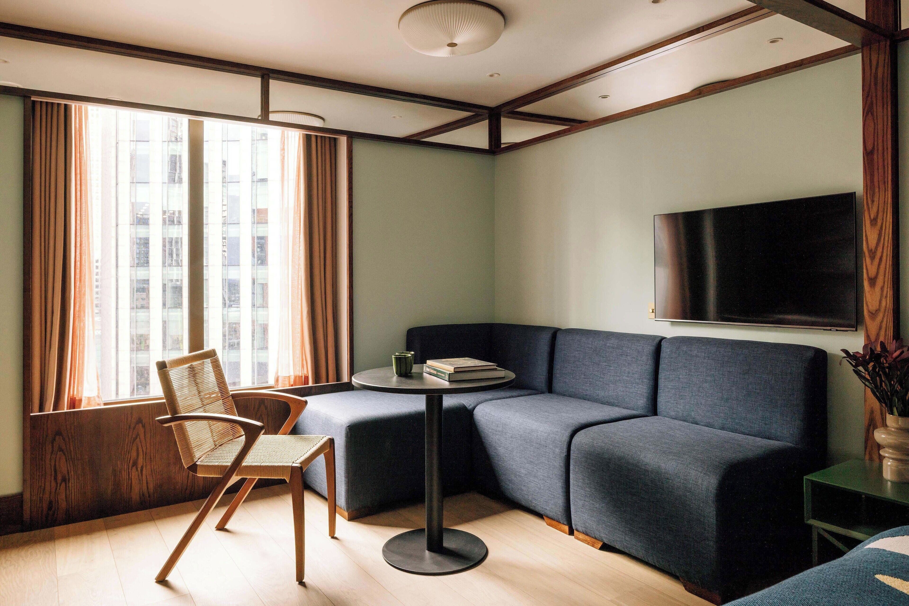A modern living room with a sectional sofa, a round coffee table, and a flat-screen TV mounted on the wall.