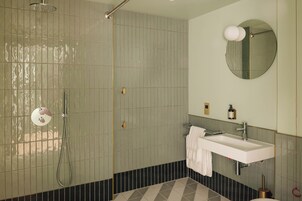 Een badkamer met een douche, wastafel en spiegel.