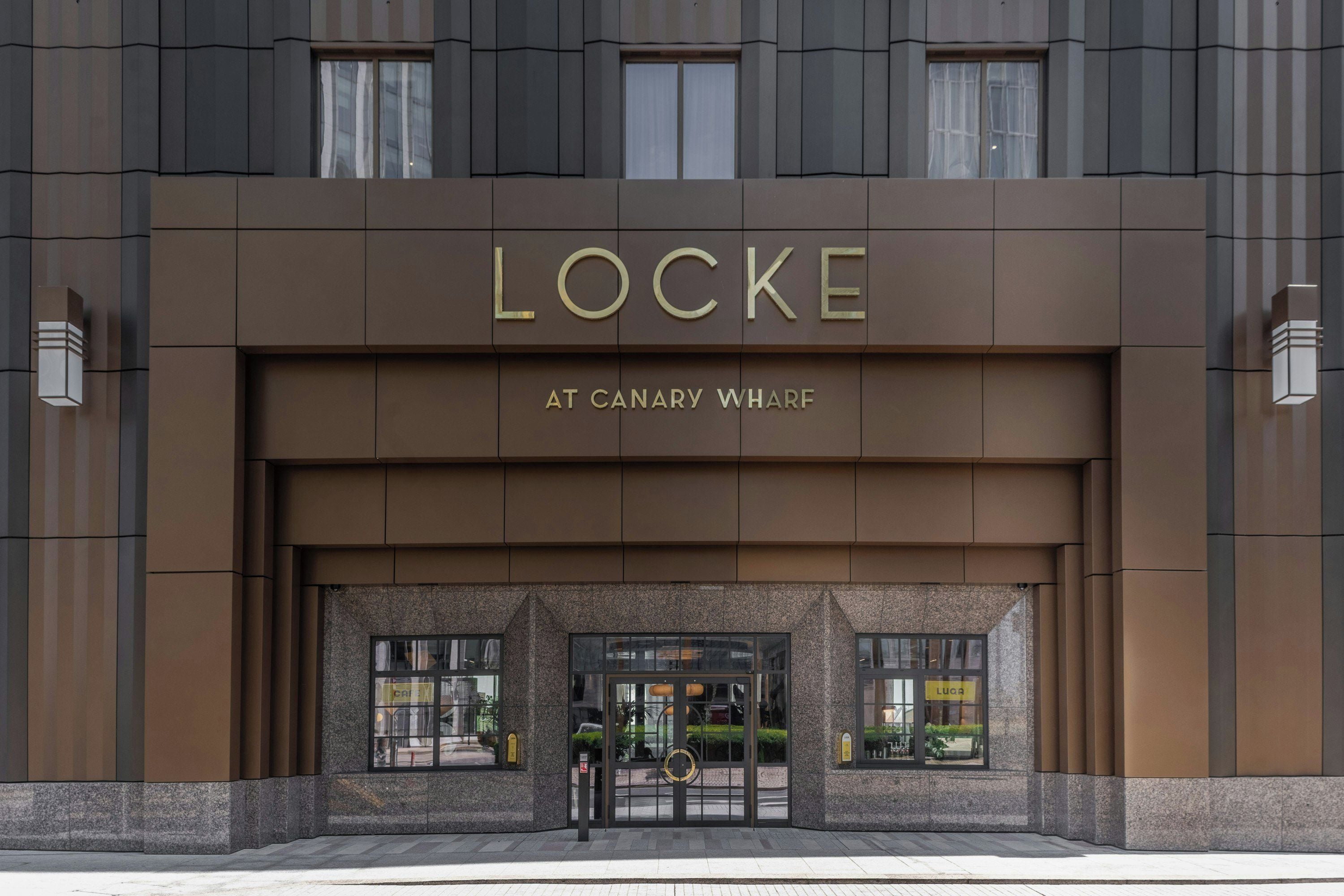 The entrance of the Locke hotel at Canary Wharf, featuring a modern facade with large windows and a prominent hotel name.