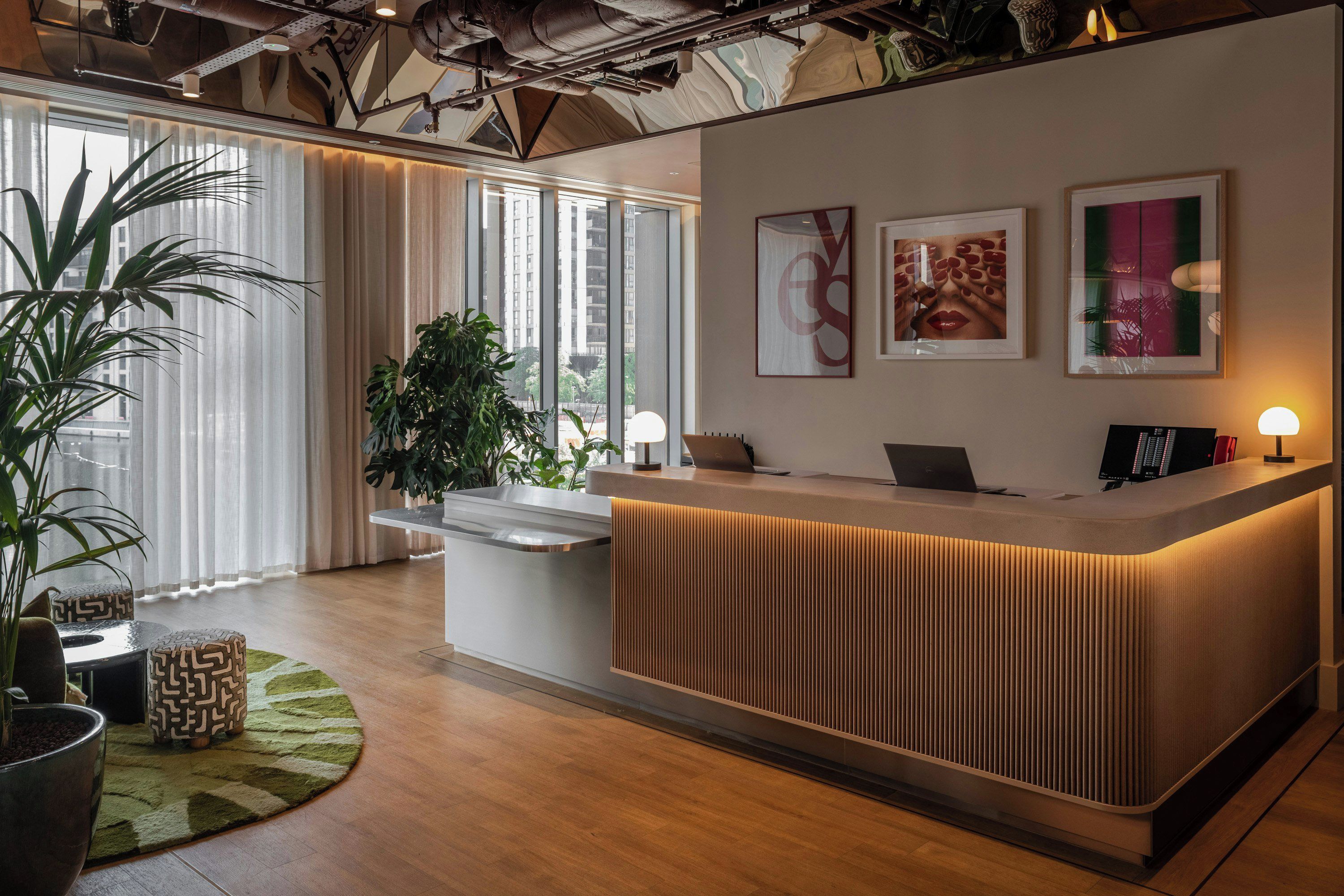 Un mostrador de recepción de diseño moderno, ventanas amplias con cortinas y vistas a la ciudad.