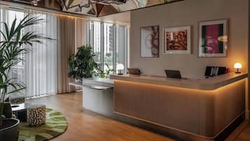 A reception desk with a modern design, large windows with curtains, and a view of the cityscape.