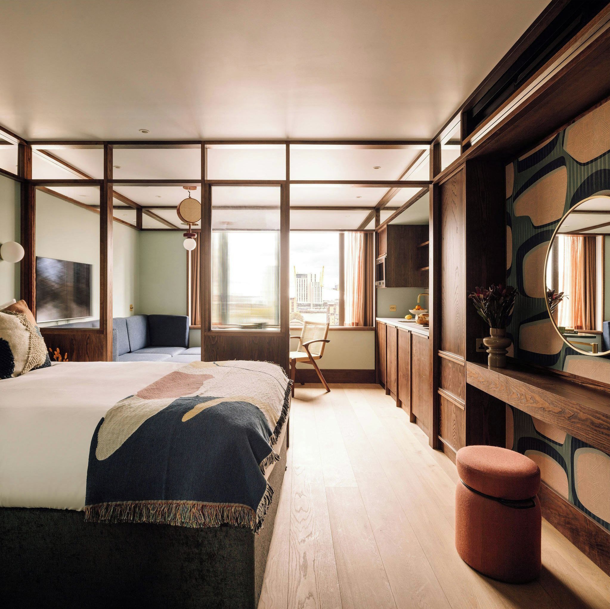 A modern bedroom with a large bed, a desk, and a view of the city.