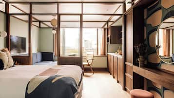 A modern bedroom with a large bed, a desk, and a view of the city.