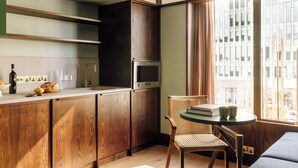 Une cuisine compacte avec des meubles en bois, un four encastré et un coin repas comprenant une table et des chaises.