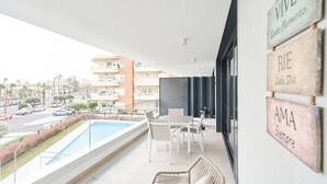 Een balkon met een zwembad, witte meubels en uitzicht op de straat.