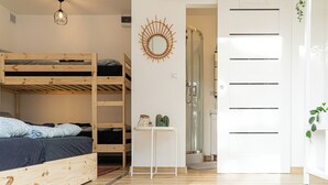 A room with a bunk bed, a small table with decorative items, a shower, and a sliding door. - SURFinn Vieux Boucau (Vieux-Boucau-les-Bains)