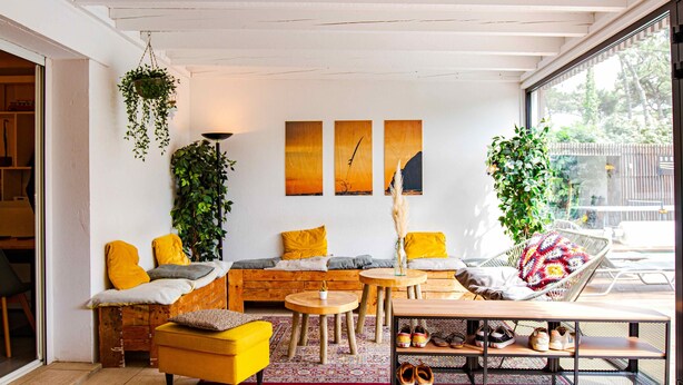 A cozy living room with a sofa, chairs, a coffee table, and a bookshelf. There is a window with a view of the outdoors. - SURFinn Vieux Boucau (Vieux-Boucau-les-Bains)