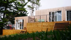 A modern wooden building with a staircase leading to a deck area, surrounded by greenery. - SURFinn Vieux Boucau (Vieux-Boucau-les-Bains)