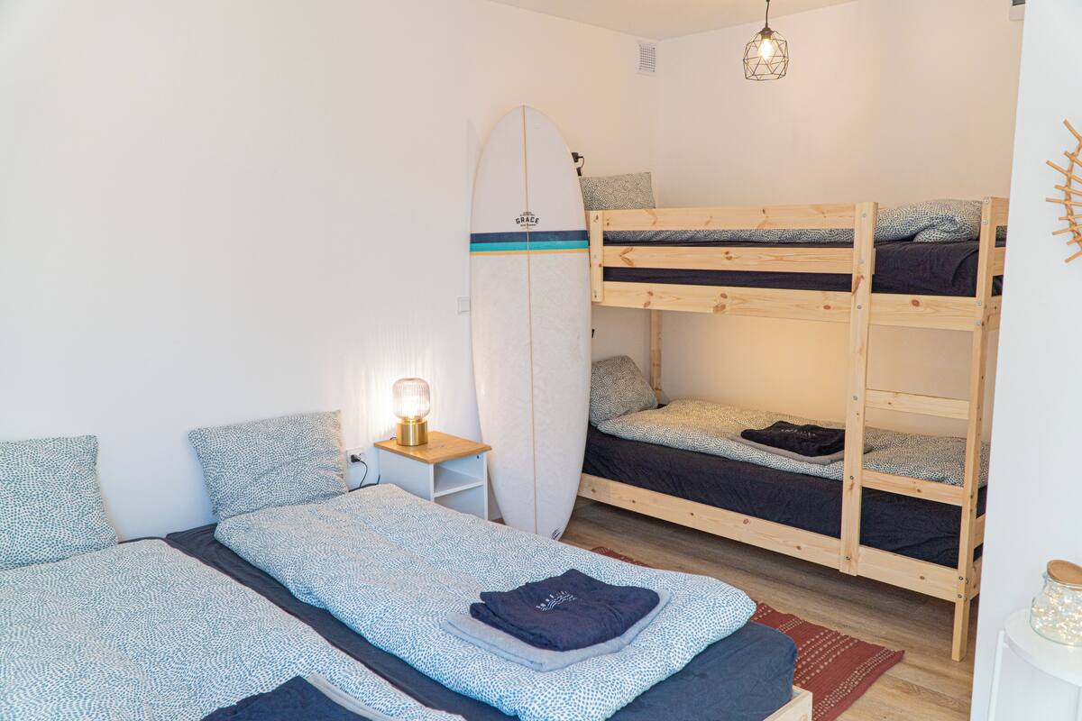 Ein Zimmer mit Etagenbetten, einem Surfbrett und einer Nachttischlampe.