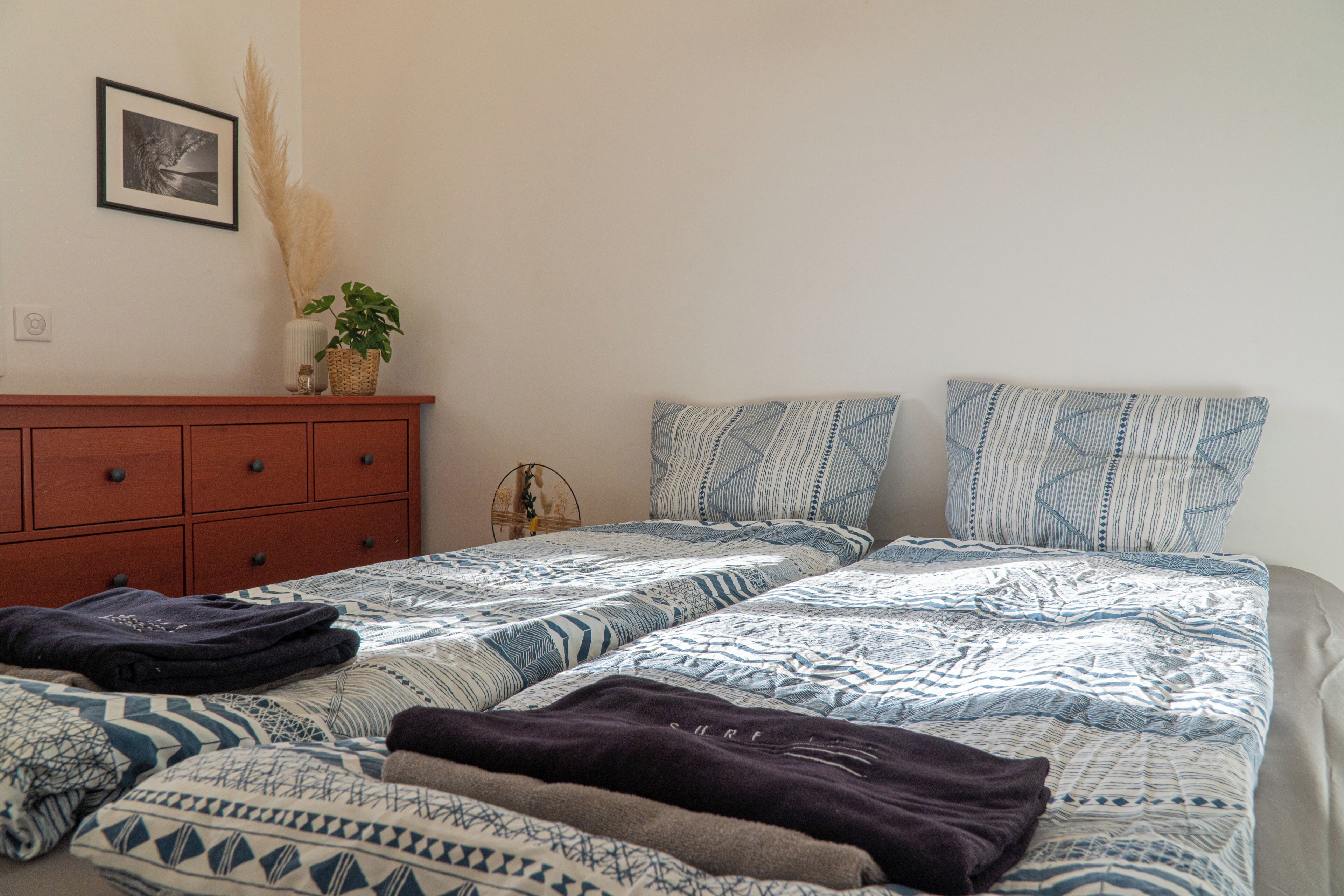 Un dormitorio con dos camas, un aparador de madera y un cuadro colgado en la pared.