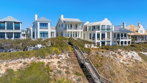 A coastal property with multiple houses, a staircase leading up a sandy hill, and a clear blue sky. - Sealah Huge Beachfront Home + Private Pool & Bikes (Inlet Beach)