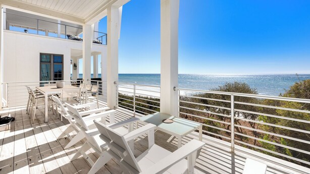 A spacious balcony with white furniture, offering a clear view of the ocean. - Sealah Huge Beachfront Home + Private Pool & Bikes (Inlet Beach)