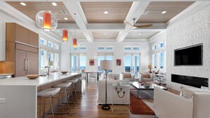 A modern kitchen with a central island, bar stools, and pendant lighting. - Sealah Huge Beachfront Home + Private Pool & Bikes (Inlet Beach)