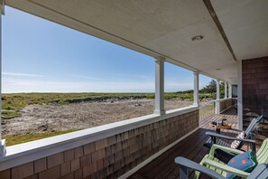 A covered outdoor area with a view of the beach, wooden deck, and lounge chairs. - NEW! Ocean View, Hot Tub, Game Room, Fire Pit (Woods) (Ocean Park)
