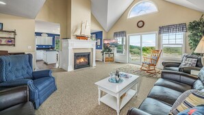 A spacious living room with a fireplace, a dining area, and a view of the outdoors. - NEW! Ocean View, Hot Tub, Game Room (Nant@Beach) (Ocean Park)