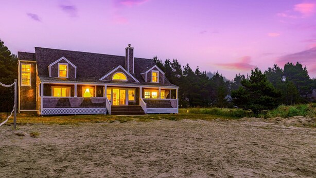 A beachfront house with a wrap-around porch, large windows, and a chimney. - NEW! Ocean View, Hot Tub, Game Room (Nant@Beach) (Ocean Park)