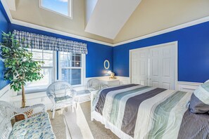 A bedroom with a large bed, a window with a view, a chair, and a small table. - NEW! Ocean View, Hot Tub, Game Room, Fire Pit (Woods) (Ocean Park)