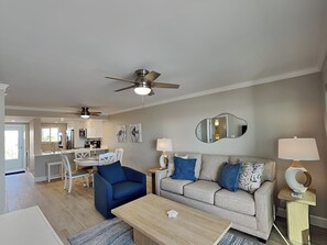 A modern living room with a sofa, coffee table, and a dining area with chairs and a table.