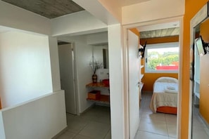 A bedroom with a bed, a window, and a desk with a computer.
