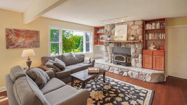 A living room with a stone fireplace, a sofa, a coffee table, and a bookshelf.