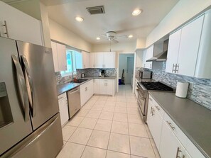 A modern kitchen with stainless steel appliances, white cabinets, and a tiled floor. - Luxury Hollywood Lakes Villa (Hollywood)